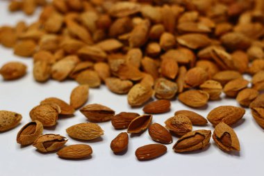 Kabukları beyaz bir yüzeye saçılmış çiğ bademler doğal dokularını ve toprak tonlarını sergiliyor. Sağlıklı yağ, protein ve vitamin içeren bademler kalp sağlığı ve beyin fonksiyonlarını destekler.