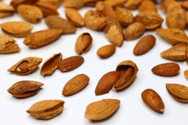 Kabukları beyaz bir yüzeye saçılmış çiğ bademler doğal dokularını ve toprak tonlarını sergiliyor. Sağlıklı yağ, protein ve vitamin içeren bademler kalp sağlığı ve beyin fonksiyonlarını destekler.