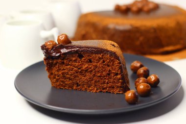 Parlak çikolata ganache ve çikolata kaplı fındıklarla kaplı zengin, nemli çikolatalı kek dilimi. Premium kakao ve bademlerden yapılmış, antioksidan ve sağlıklı yağ sunuyor.