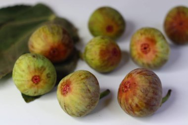 Beyaz arka planda yeşil yapraklı taze incirler. Yüksek miktarda lif, antioksidan ve vitamin sindirime ve sağlığa yardımcı olur. Gıda blogları, beslenme alanları ve stok fotoğrafçılığı için ideal.