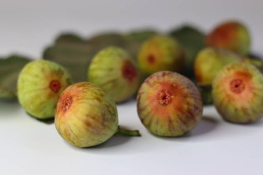 Beyaz arka planda yeşil yapraklı taze incirler. Yüksek miktarda lif, antioksidan ve vitamin sindirime ve sağlığa yardımcı olur. Gıda blogları, beslenme alanları ve stok fotoğrafçılığı için ideal.