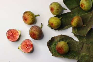Beyaz arka planda yeşil yapraklı taze incirler. Yüksek miktarda lif, antioksidan ve vitamin sindirime ve sağlığa yardımcı olur. Gıda blogları, beslenme alanları ve stok fotoğrafçılığı için ideal.