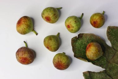 Beyaz arka planda yeşil yapraklı taze incirler. Yüksek miktarda lif, antioksidan ve vitamin sindirime ve sağlığa yardımcı olur. Gıda blogları, beslenme alanları ve stok fotoğrafçılığı için ideal.