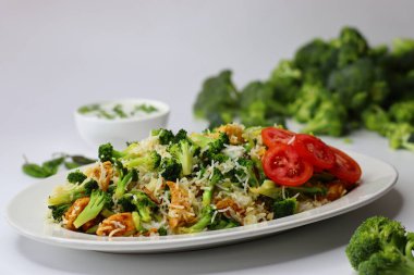 Raita ile brokoli tavuklu pilav. Yumuşak kızarmış tavuk, taze brokoli ve kremalı raita ile servis edilen yumuşacık pilav içeren besleyici bir yemek. Protein, lif ve soğutma lezzetleriyle dolu.