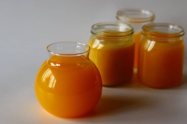 Ev yapımı İnek Ghee. Süt katı maddeleri ve su buharlaşana kadar yavaş ısıtılan tereyağı ile yapılan berrak bir tereyağı zengin bir aroması ve derin bir tadı olan altın, berrak bir sıvı oluşturur. Cam şişelerde depolanmış.