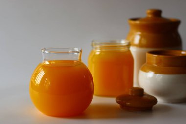 Ev yapımı İnek Ghee. Süt katı maddeleri ve su buharlaşana kadar yavaş ısıtılan tereyağı ile yapılan berrak bir tereyağı zengin bir aroması ve derin bir tadı olan altın, berrak bir sıvı oluşturur. Cam şişelerde depolanmış.