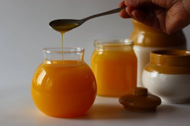 Ev yapımı İnek Ghee. Süt katı maddeleri ve su buharlaşana kadar yavaş ısıtılan tereyağı ile yapılan berrak bir tereyağı zengin bir aroması ve derin bir tadı olan altın, berrak bir sıvı oluşturur. Cam şişelerde depolanmış.