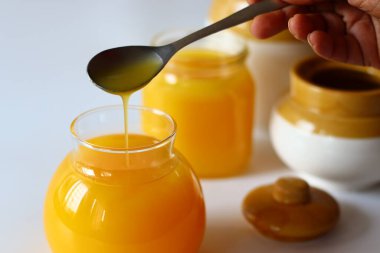 Ev yapımı İnek Ghee. Süt katı maddeleri ve su buharlaşana kadar yavaş ısıtılan tereyağı ile yapılan berrak bir tereyağı zengin bir aroması ve derin bir tadı olan altın, berrak bir sıvı oluşturur. Cam şişelerde depolanmış.