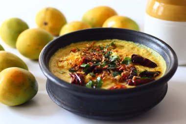 Kerala usulü körili yoğurt, hindistan cevizi ve baharatla pişirilmeye hazır toprakta soyulmuş mangolar. Adı Mango Pulisheri, ayrıca olgun mangolu yoğurt körisi, Kerala usulü mango körisi.