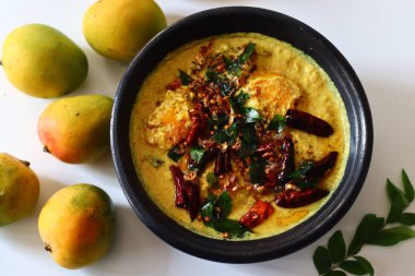 Kerala usulü körili yoğurt, hindistan cevizi ve baharatla pişirilmeye hazır toprakta soyulmuş mangolar. Adı Mango Pulisheri, ayrıca olgun mangolu yoğurt körisi, Kerala usulü mango körisi.