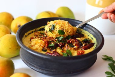 Kerala usulü körili yoğurt, hindistan cevizi ve baharatla pişirilmeye hazır toprakta soyulmuş mangolar. Adı Mango Pulisheri, ayrıca olgun mangolu yoğurt körisi, Kerala usulü mango körisi.