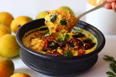 Kerala usulü körili yoğurt, hindistan cevizi ve baharatla pişirilmeye hazır toprakta soyulmuş mangolar. Adı Mango Pulisheri, ayrıca olgun mangolu yoğurt körisi, Kerala usulü mango körisi.