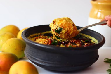 Kerala usulü körili yoğurt, hindistan cevizi ve baharatla pişirilmeye hazır toprakta soyulmuş mangolar. Adı Mango Pulisheri, ayrıca olgun mangolu yoğurt körisi, Kerala usulü mango körisi.