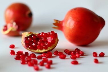 - Nar. Beyaz bir yüzeyde parlak kırmızı şeritli açık meyve, yumuşak doğal ışıkla yakalanır. Antioksidan, C vitamini ve lif açısından zengin. Kalp sağlığını ve sindirimi destekliyor.