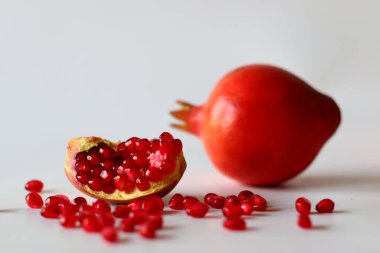 - Nar. Beyaz bir yüzeyde parlak kırmızı şeritli açık meyve, yumuşak doğal ışıkla yakalanır. Antioksidan, C vitamini ve lif açısından zengin. Kalp sağlığını ve sindirimi destekliyor.