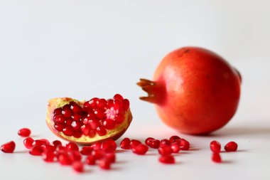 - Nar. Beyaz bir yüzeyde parlak kırmızı şeritli açık meyve, yumuşak doğal ışıkla yakalanır. Antioksidan, C vitamini ve lif açısından zengin. Kalp sağlığını ve sindirimi destekliyor.