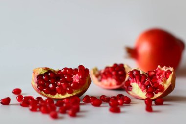 - Nar. Beyaz bir yüzeyde parlak kırmızı şeritli açık meyve, yumuşak doğal ışıkla yakalanır. Antioksidan, C vitamini ve lif açısından zengin. Kalp sağlığını ve sindirimi destekliyor.