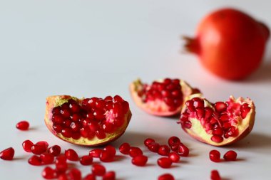 - Nar. Beyaz bir yüzeyde parlak kırmızı şeritli açık meyve, yumuşak doğal ışıkla yakalanır. Antioksidan, C vitamini ve lif açısından zengin. Kalp sağlığını ve sindirimi destekliyor.