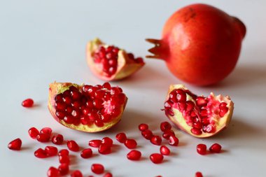 - Nar. Beyaz bir yüzeyde parlak kırmızı şeritli açık meyve, yumuşak doğal ışıkla yakalanır. Antioksidan, C vitamini ve lif açısından zengin. Kalp sağlığını ve sindirimi destekliyor.