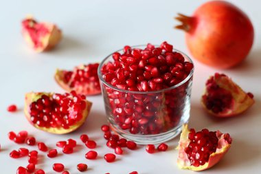 - Nar. Beyaz bir yüzeyde parlak kırmızı şeritli açık meyve, yumuşak doğal ışıkla yakalanır. Antioksidan, C vitamini ve lif açısından zengin. Kalp sağlığını ve sindirimi destekliyor.