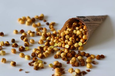 Crispy Roasted Channa chickpeas in a newspaper cone, scattered on white background. Perfect for Indian snacks, protein rich diets, healthy eating themes. Ideal for clean eating and vegan food image
