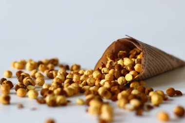 Crispy Roasted Channa chickpeas in a newspaper cone, scattered on white background. Perfect for Indian snacks, protein rich diets, healthy eating themes. Ideal for clean eating and vegan food image