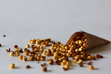 Crispy Roasted Channa chickpeas in a newspaper cone, scattered on white background. Perfect for Indian snacks, protein rich diets, healthy eating themes. Ideal for clean eating and vegan food image