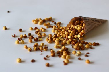 Crispy Roasted Channa chickpeas in a newspaper cone, scattered on white background. Perfect for Indian snacks, protein rich diets, healthy eating themes. Ideal for clean eating and vegan food image