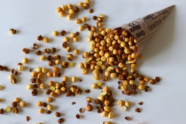 Crispy Roasted Channa chickpeas in a newspaper cone, scattered on white background. Perfect for Indian snacks, protein rich diets, healthy eating themes. Ideal for clean eating and vegan food image