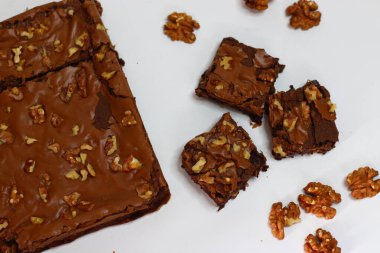 Cevizli, zengin, çikolatalı browni üzerine cevizli kek, fırın zeminine kurulmuş. Lezzetli yemek fotoğrafçılığı, yemek blogları ve görsel tedavi için mükemmel bir Amerikan tatlısı.