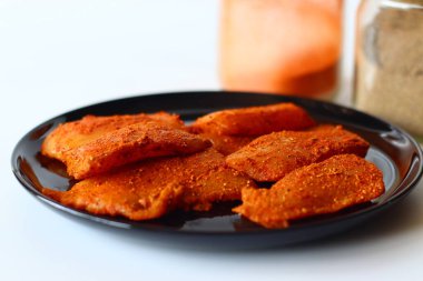 Çiğ tilapia filetosu koyu Hint baharatı karışımı kırmızı biber, zerdeçal, biber ve tuz ile marine edilmiş, siyah bir tabakta. Ev yapımı balık körisi, desi mutfağı ya da lezzetli deniz ürünleri hazırlamak için ideal.