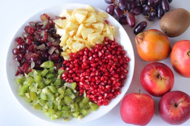 Meyve tabağı. Nar tohumlu canlı meyve tabağı, doğranmış kivi üzümü ve elma. Üzüm ve meyvelerle çevrili, vejetaryen mutfağı, sağlıklı beslenme, sağlık ve yemek fotoğrafçılığı için mükemmel.