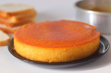 Karamelli ekmek pudingi, parlak altın kaplamalı, yeni demlenmiş ve siyah bir tabakta servis edilmiş. Ekmek, süt, yumurta ve karamel ile yapılan zengin bir Anglo-Hint tatlısı, şenlikli yemek temaları için mükemmel.