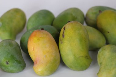 Raseeli mangoları, yeşilden turuncuya kadar çeşitli olgunlukta. Tazelik, mevsimlik ve doğa temaları için ideal tropik bir Güney Asya meyvesi.