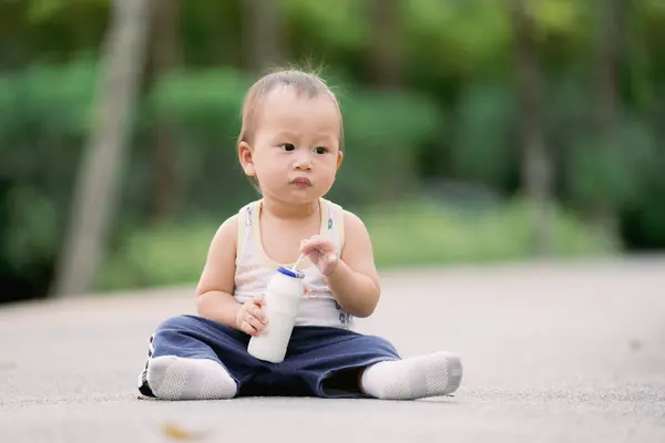 亚洲男婴在瓶子里用管子喝牛奶 Toddler 1岁坐在地板上 那孩子的嘴上布满了牛奶 — 图库照片