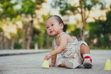 1 yaşındaki bir çocuk yürümeyi öğreniyor, çocuk yere düşüyor ve kaldırıma oturuyor, bir çocuk ilk neşeli adımlarını atıyor. İşaretleyici külahlarla oynayan çocuklar.