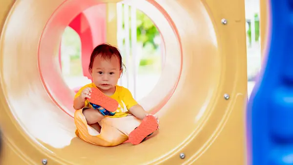 아시아 소년은 공원에서 시간을 즐긴다 놀이터에서 오렌지 노란색 장난감 터널에 로열티 프리 스톡 이미지