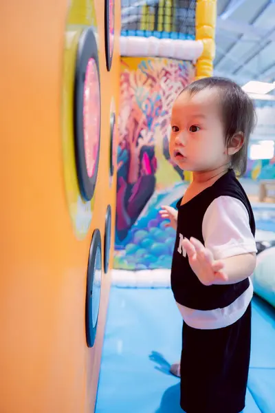 stock image Child playing game of chasing flashing lights, body movement, acumen, observation and agility, learning and muscle development, boy playing happily in playground room, one year and five month old kid.