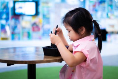 Tatlı Asyalı kız siyah plastik bir kutuda oturur ve yemek yer. Küçük liseli kız okuldan sonra yemek yer. Çocuklar kendi yemeklerini yerler. Beş yaşında bir çocuk..