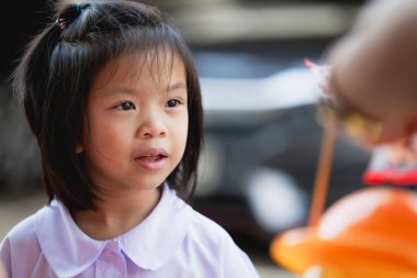 Parkta oynarken gülümseyen neşeli küçük bir kızın portresi. Okul üniformasıyla, okuldan sonra. Uzayı kopyala 7 yaşındaki Asyalı Çocuk.