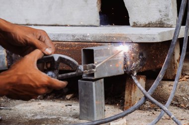 Etrafında çeşitli aletler ve ekipmanlarla bir atölyede çalışan bir demirci, ısı ve yangınla metal üretiyor ve kesiyor..