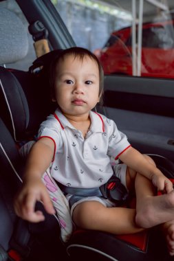 Mutlu bir erkek bebek güvenli bir şekilde bir araba koltuğuna oturmuş ailesiyle seyahat ederken parlak bir şekilde gülümsüyor. Bebek 1-2 yaşlarındaydı..