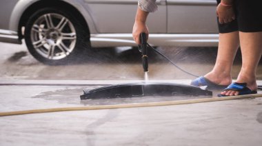Güneşli bir günde araba yıkamak için yüksek basınçlı bir hortum tutan birinin yakın çekimi. Araba yıkama. Araba temizliği. Yüksek Basınçlı Su Kullanılıyor.