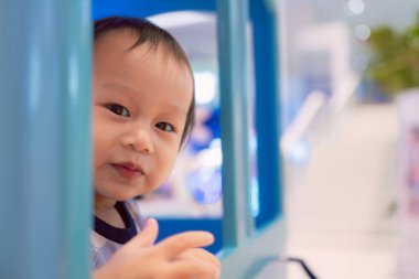 Oyun parkında oyuncak trende oynayan gülümseyen küçük bir çocuğun portresi, sevimli yüzü ve küçük saçlarıyla mutlu görünüyor. Asyalı çocuk 1 yaşında..