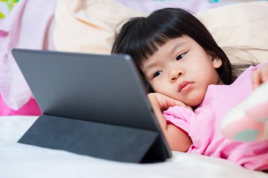 Asyalı bir çocuk dizüstü bilgisayar kullanarak evde öğrenme ve teknoloji gösterisi yapıyor. Genç kız videoyu dikkatle izliyor. 4 yaşında tatlı bir çocuk..