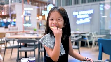 Şirin Asyalı kız restoranda mutlu bir şekilde kraker yiyor..