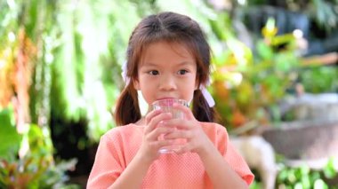 Gülümseyen çocuk bardaktan temiz su içiyor. Su dengesi ve sağlık hizmeti kavramı.