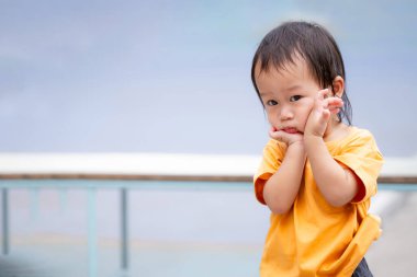 Sevimli Asyalı çocuk yabancı insanlarla tanıştığında utangaç ve güvensiz davranıyor. Çocukluğun masumiyetini yakalamak. 1-2 yaşlarındaki çocuklar.