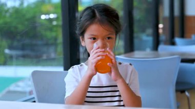 Gülümseyen bir çocuk kapalı bir restoranda portakal suyu yemekten ve içmekten hoşlanır. Sağlıklı bir vücut için meyve suyu iç ve vitaminlerini arttır..