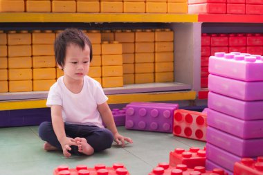 Küçük Çocuk evde ya da evin içinde renkli oyuncak bloklarıyla mutlu bir şekilde oynuyor. 2 yaşında bir bebek..